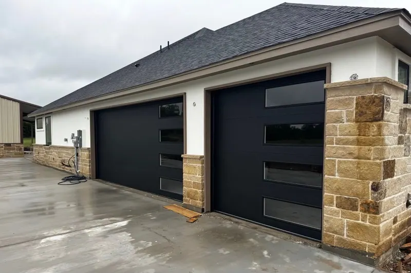Black glass and aluminum garage door on a white stucco and stone home