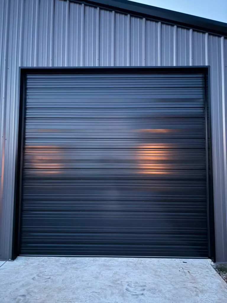 Black roll up door installed on a metal shop building