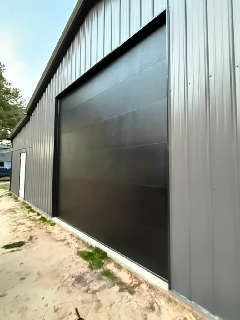 Black flush overhead door on a gray metal commercial building
