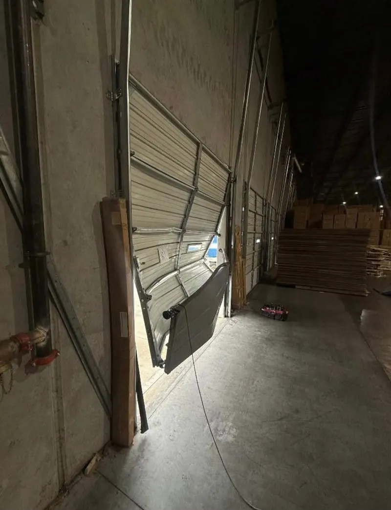 Off track garage door being repaired inside a warehouse in Fort Worth