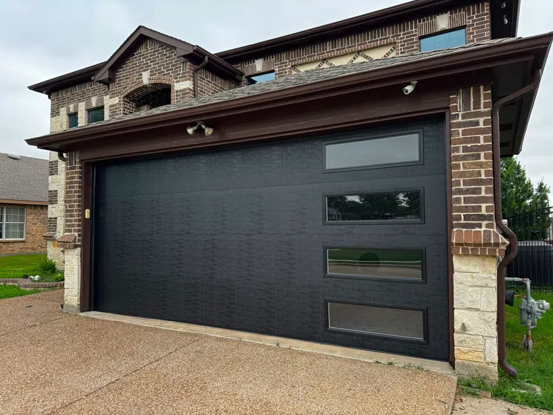 Luxury black glass and aluminum garage door on a brick and stone estate in the Dallas Fort Worth area