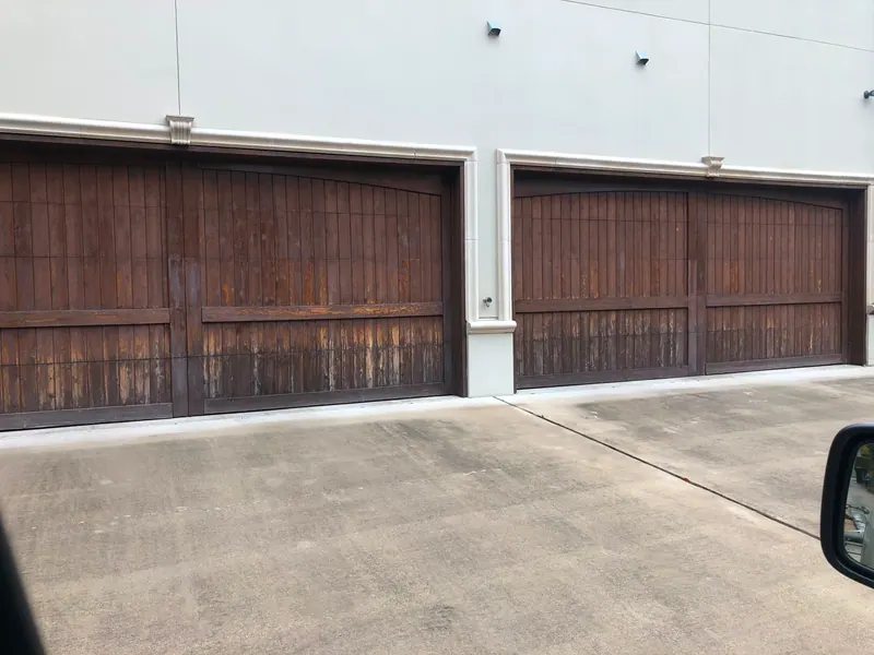 Two wood look double carriage garage doors on a multi unit building